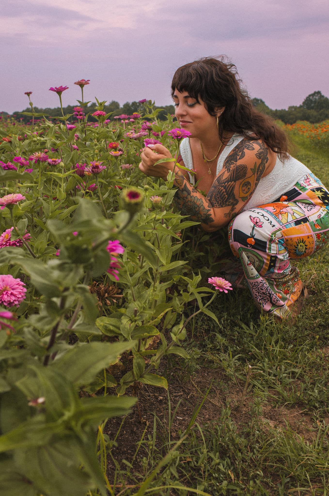 J.J. crouching among pink flowers and holding one bloom.